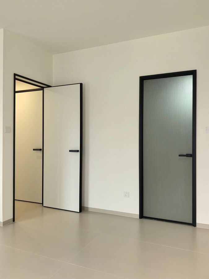 A black-framed door half open beside a reeded glass door