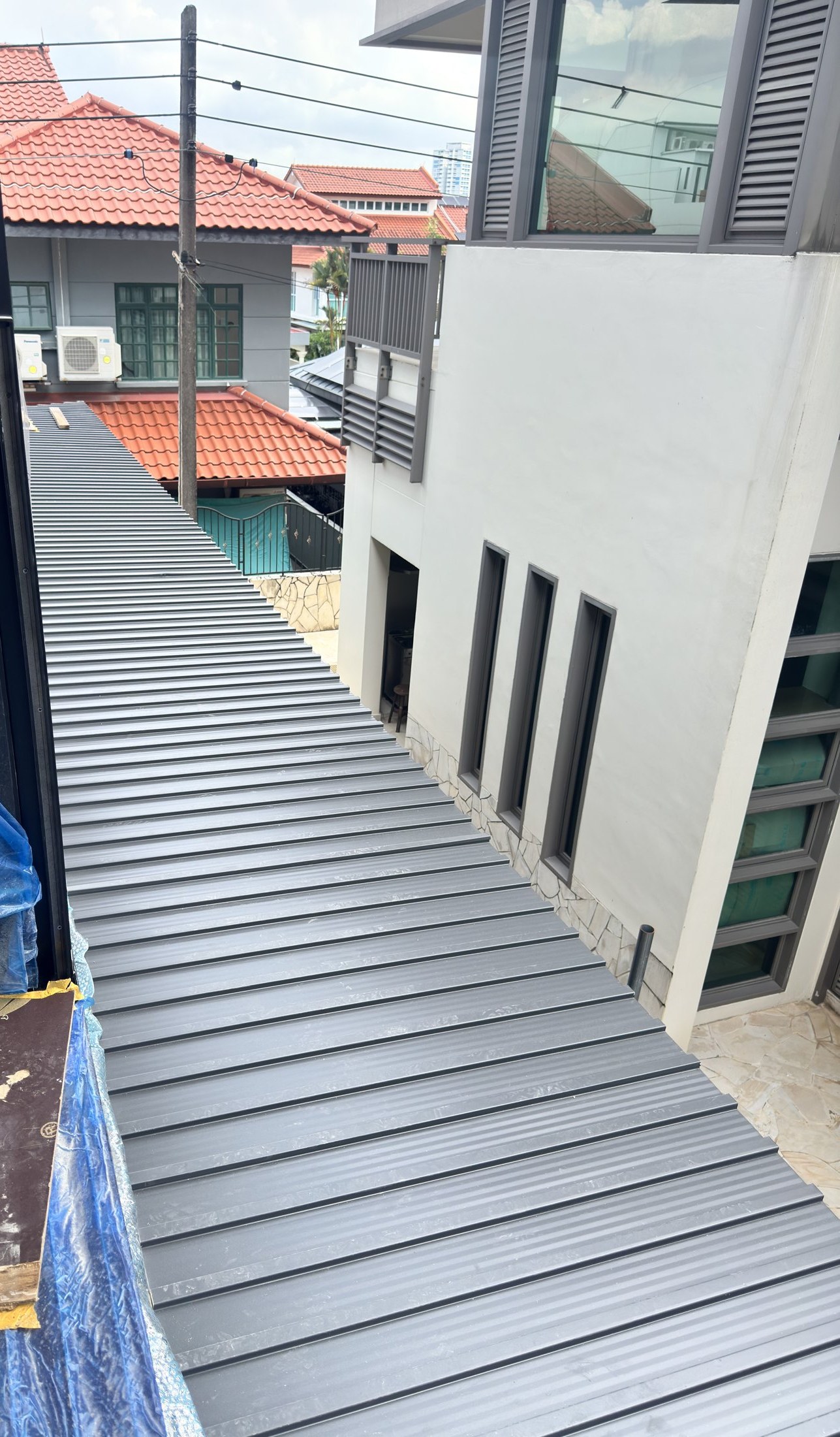 A run of insulated aluminium roof panel down the side of a Singapore house